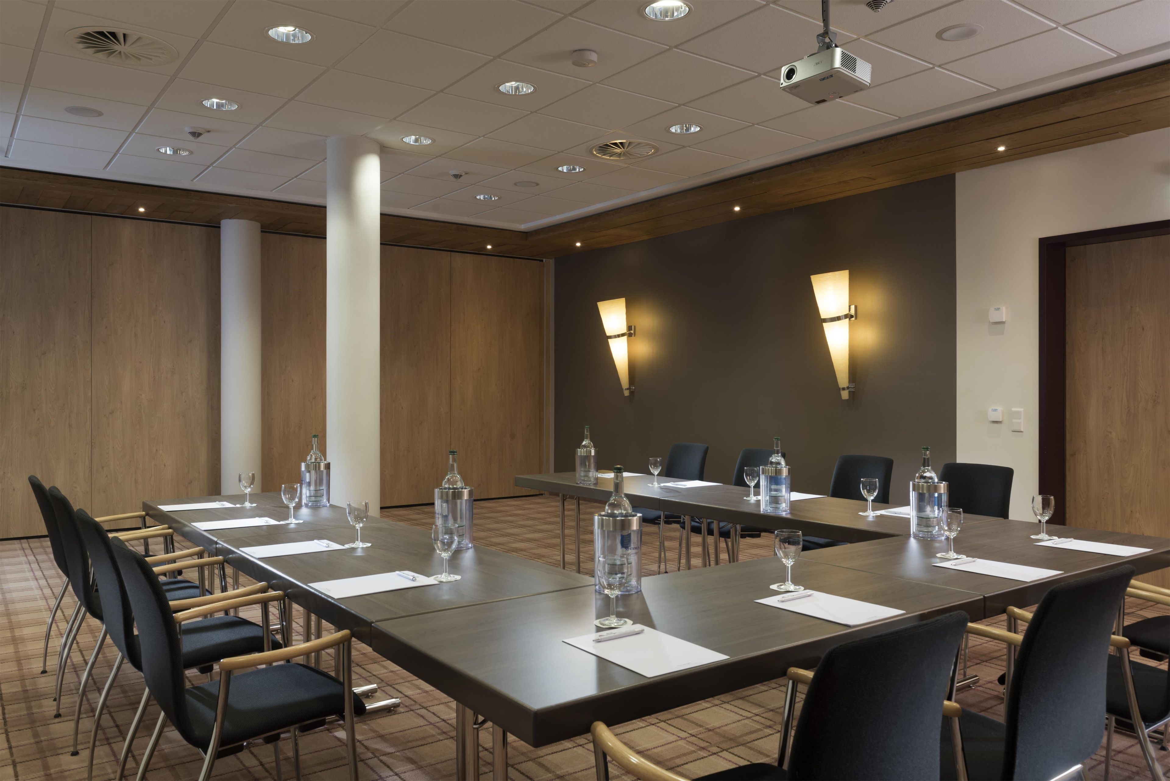 A conference room with a long table, chairs, water bottles, and glasses.