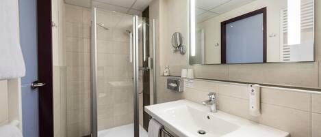 A modern bathroom with a glass shower enclosure, a white sink, and a large mirror.