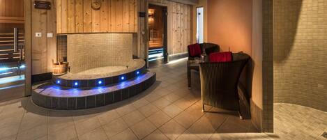 A spa area with a hot tub, seating, and a wooden wall.