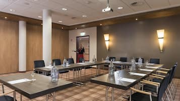 A conference room with long tables, chairs, and a person standing near the door.