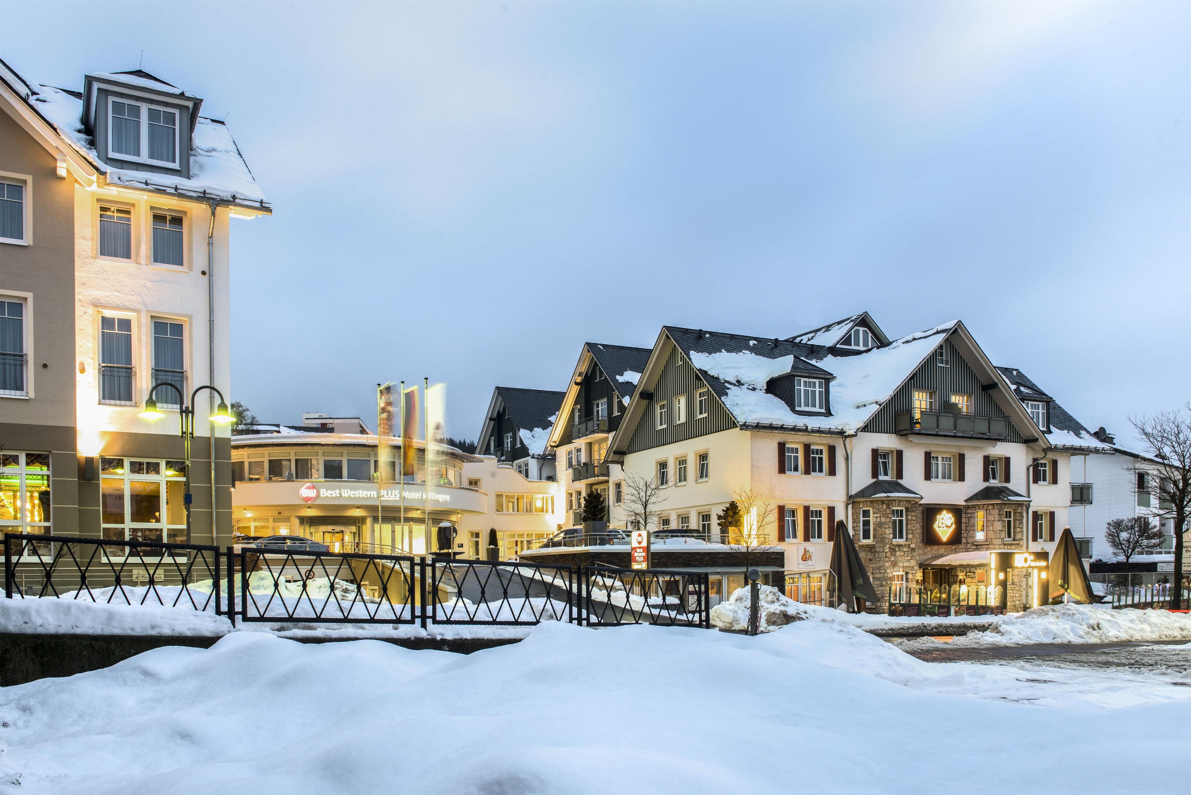 Ein mehrstöckiges Hotel, verschneiter Boden und eine Brücke im Vordergrund.