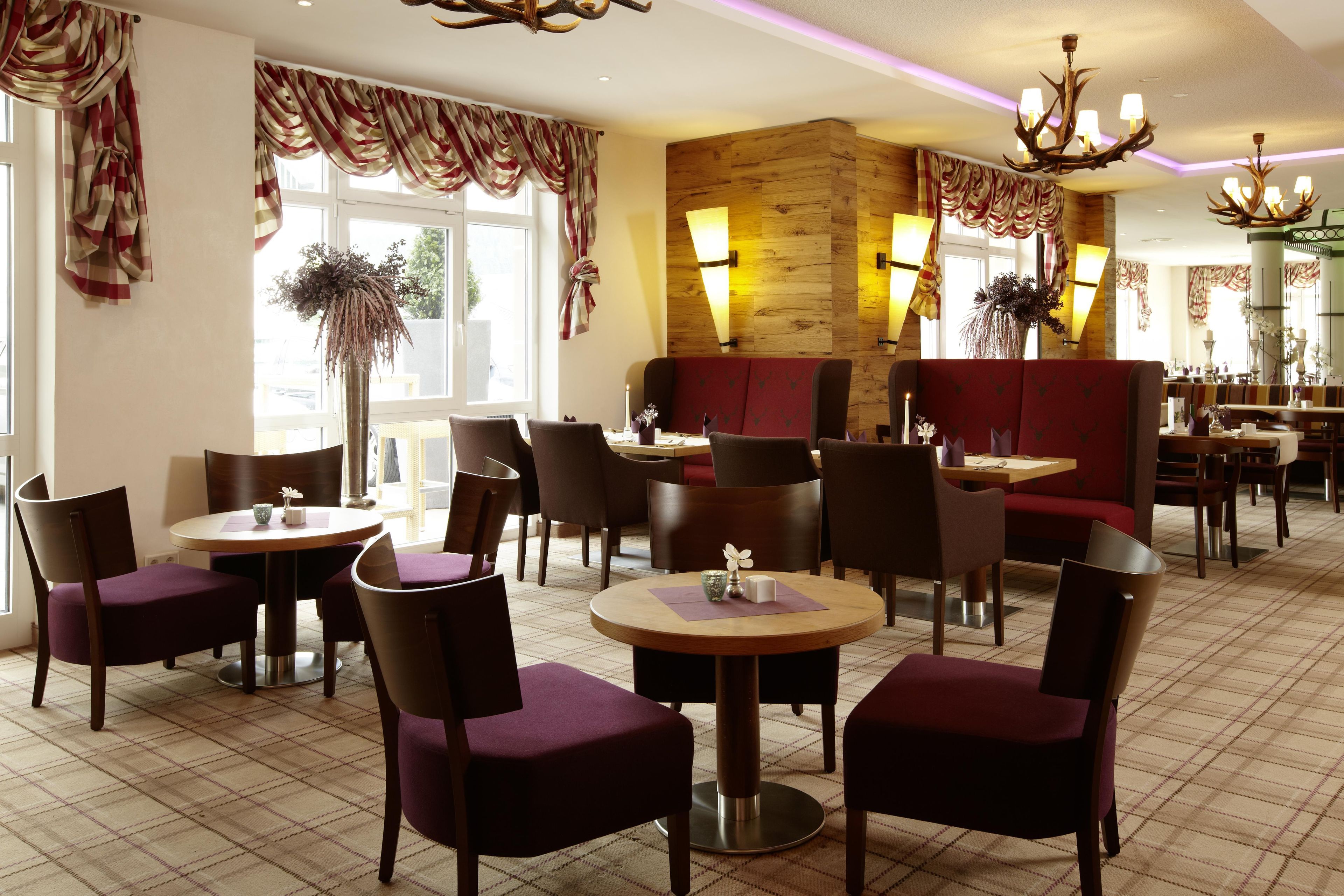 A restaurant interior with round tables, chairs, and a wooden accent wall.