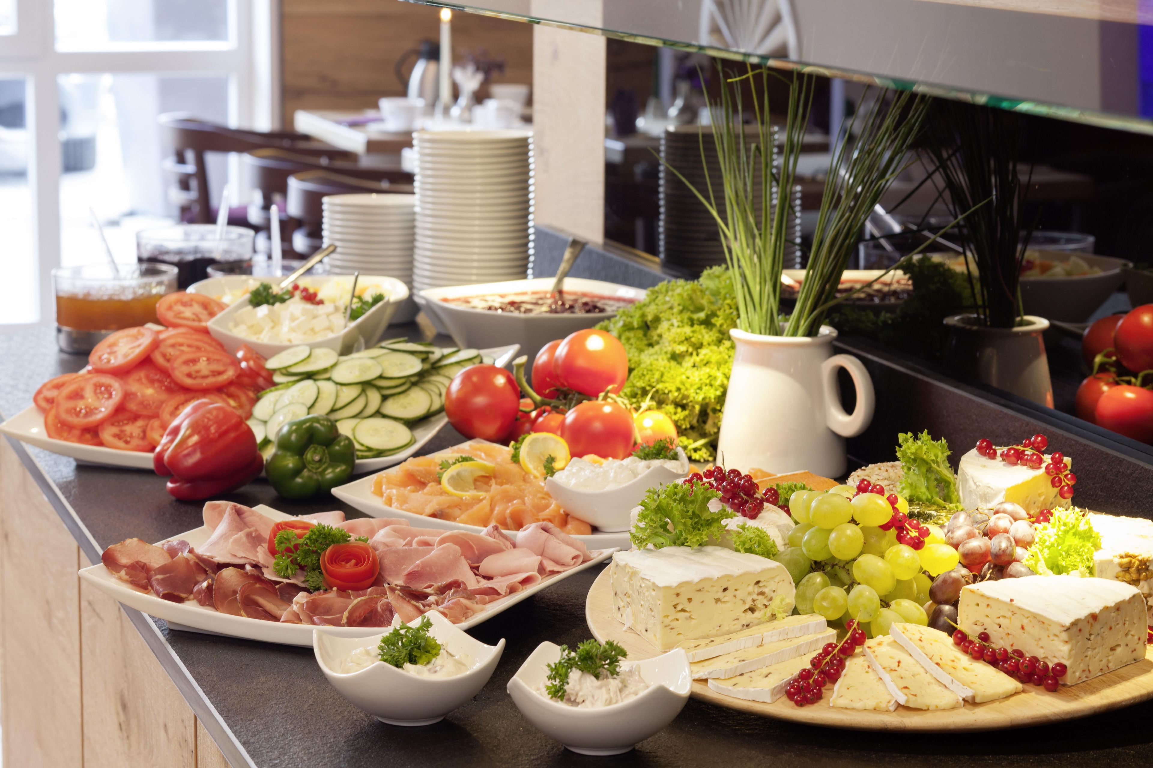 A buffet with various food items including meats, cheeses, fruits, and vegetables.
