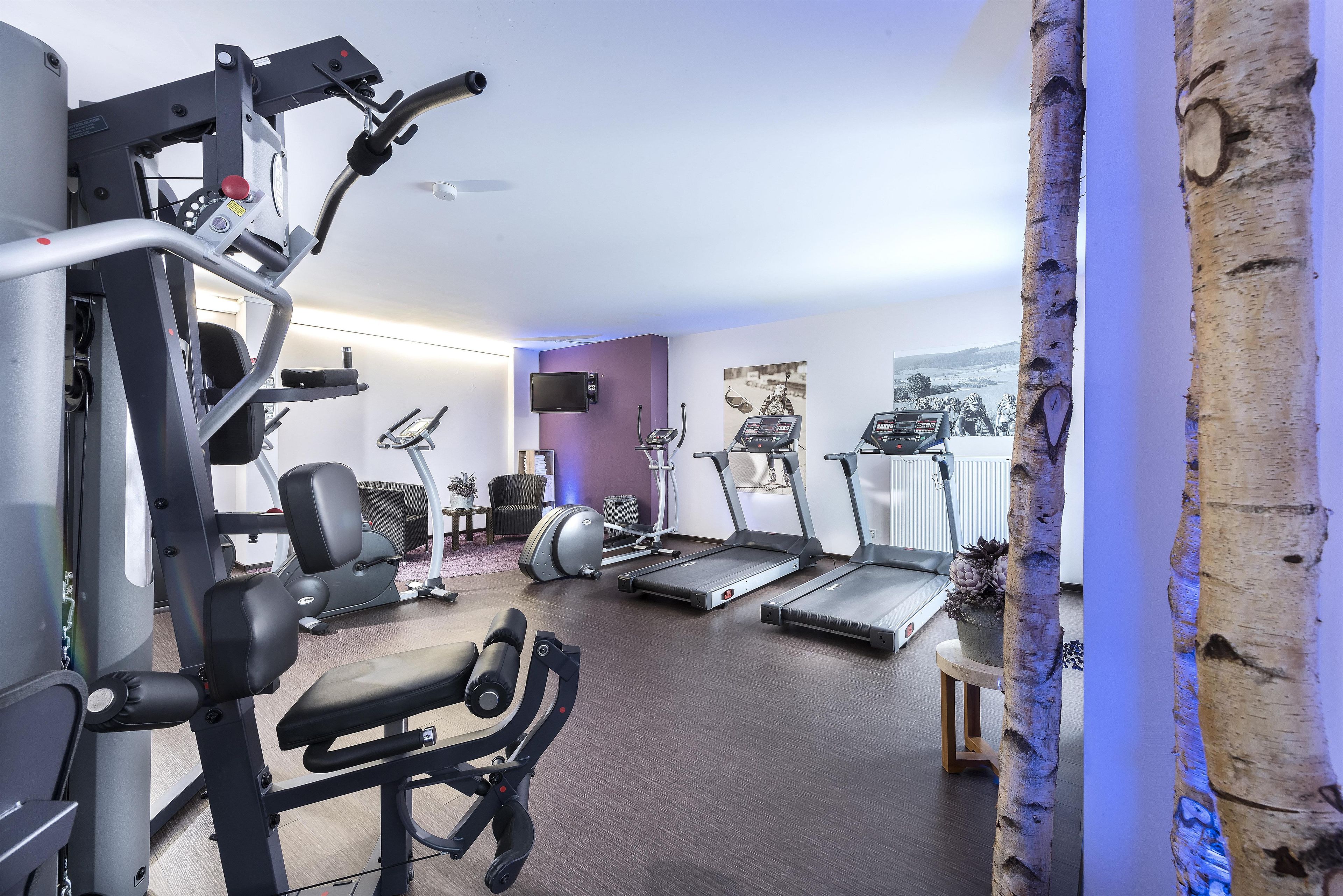 A gym with exercise equipment, treadmills, and a wall-mounted TV.