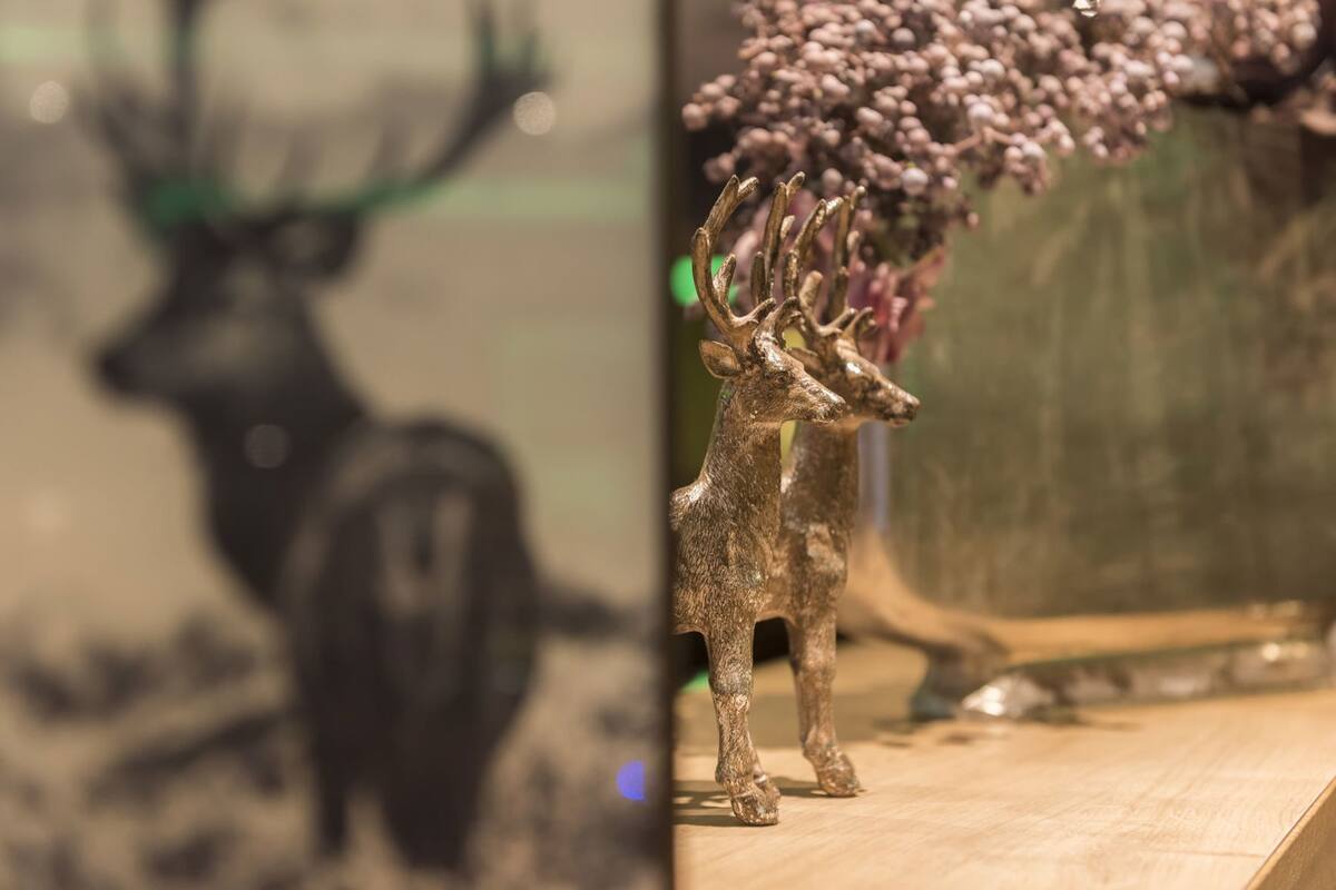 Un gros plan d’une figurine de cerf et d’un vase contenant des fleurs violettes.