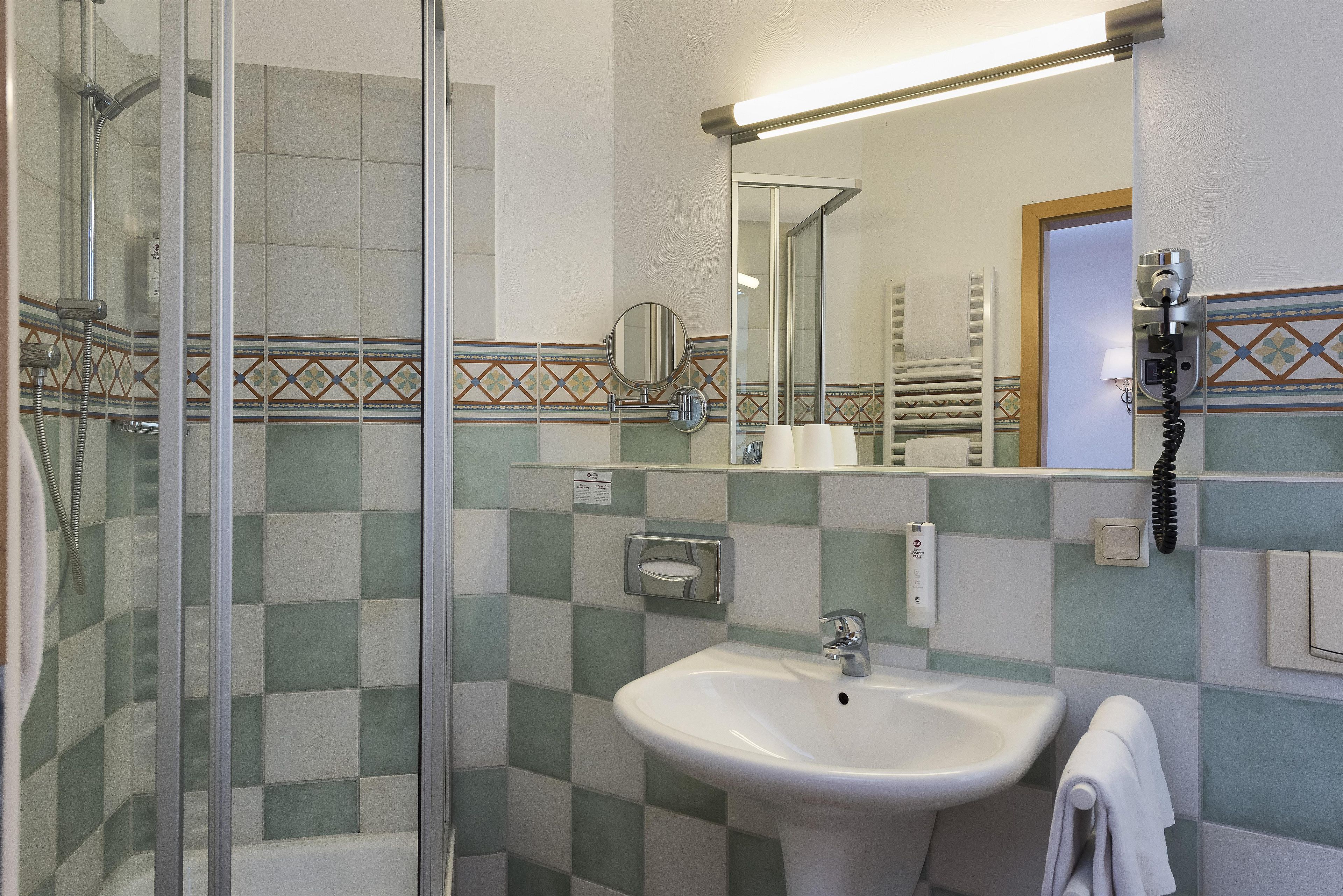 Ein Badezimmer mit Dusche, Waschbecken, Spiegel und Handtuchhalter.