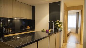 A modern kitchen with a black marble countertop, wooden cabinets, and a built-in coffee maker.