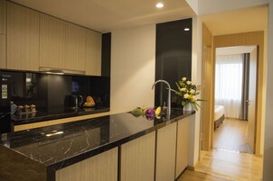 A modern kitchen with a black marble countertop, wooden cabinets, and a built-in coffee maker.