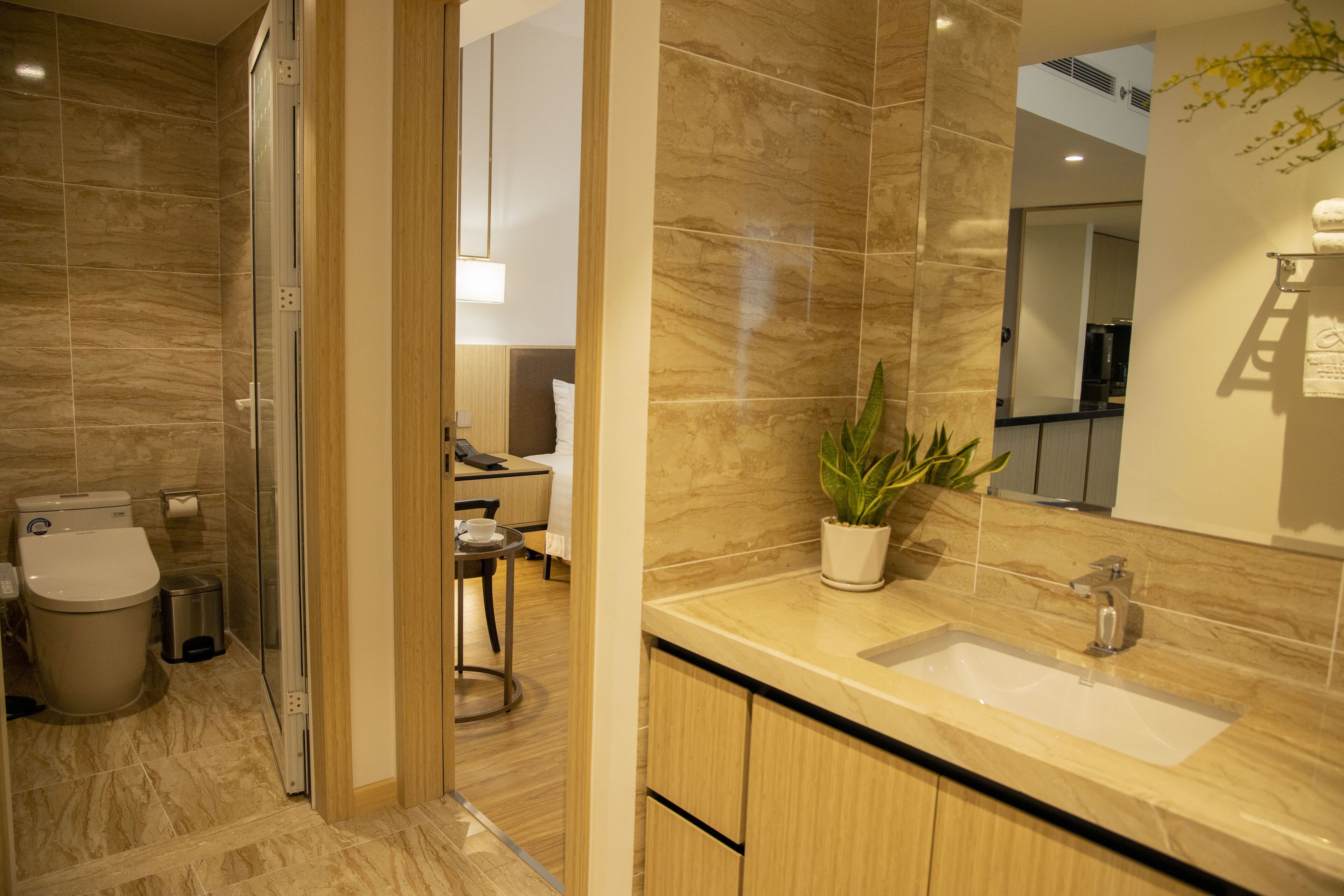 A modern bathroom with a sink, mirror, and potted plant.