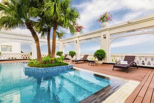 Una piscina al aire libre, sombrillas, sillones reclinables de piscina