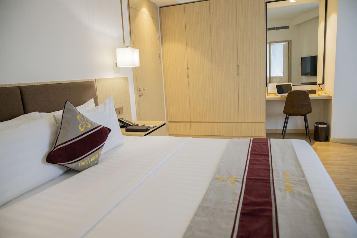 A hotel room with a bed, a desk, a chair, and a wardrobe.