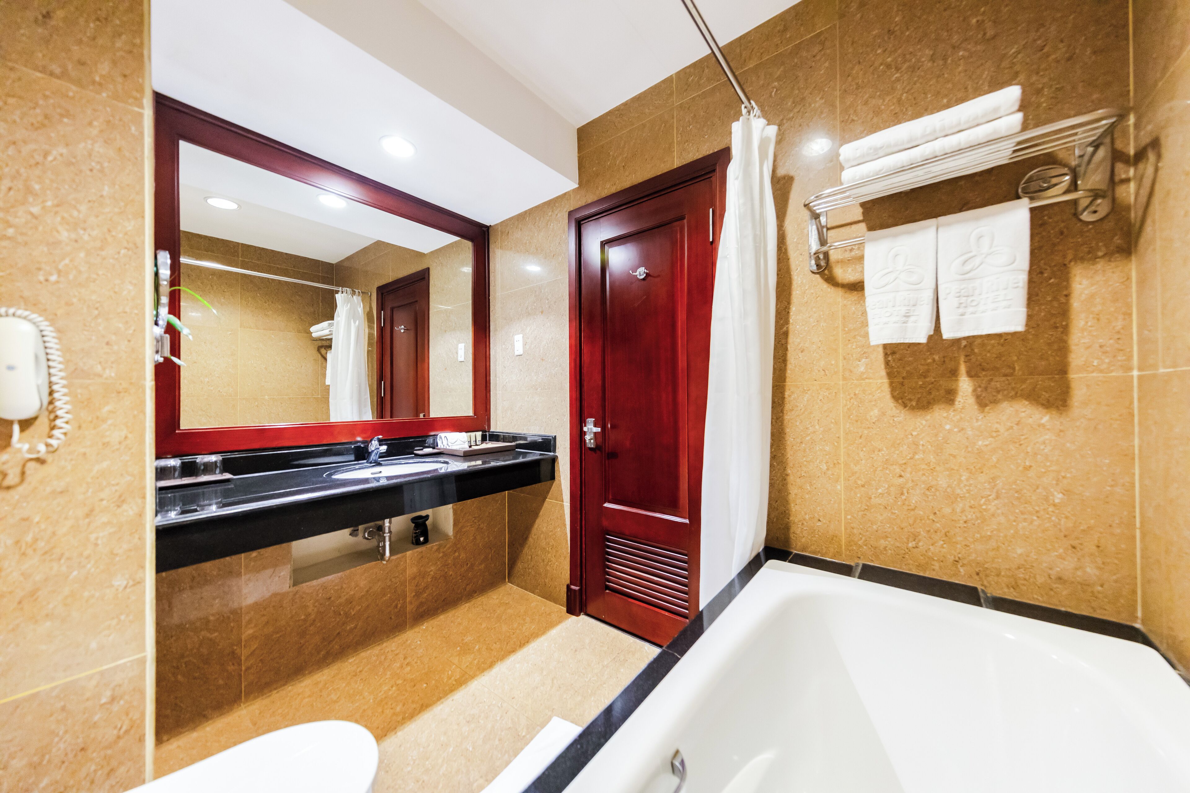 Un baño con bañera, lavamanos doble, espejo y toallero.