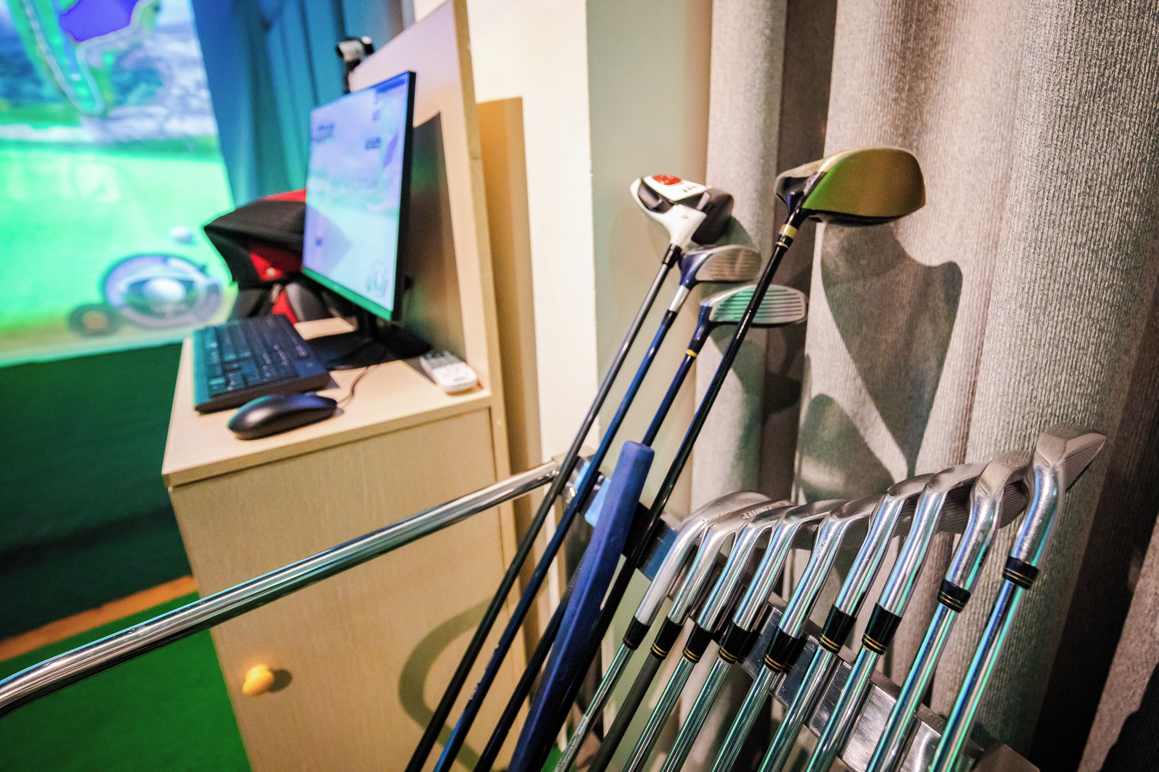 Un porte-clubs de golf contenant plusieurs clubs, un écran d’ordinateur et un clavier, le tout posé sur un bureau.