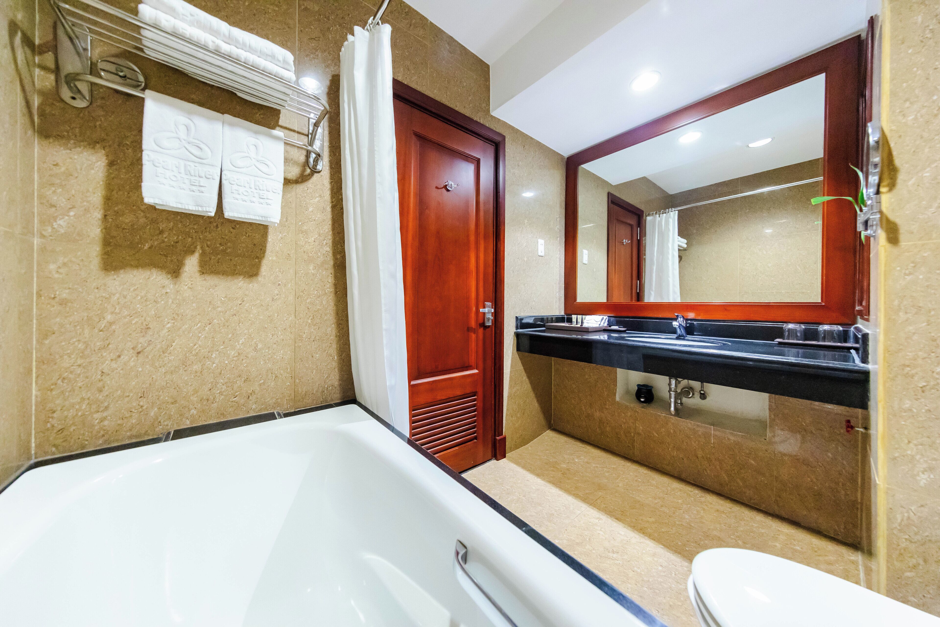 A bathroom with a bathtub, a toilet, a sink, and a mirror.