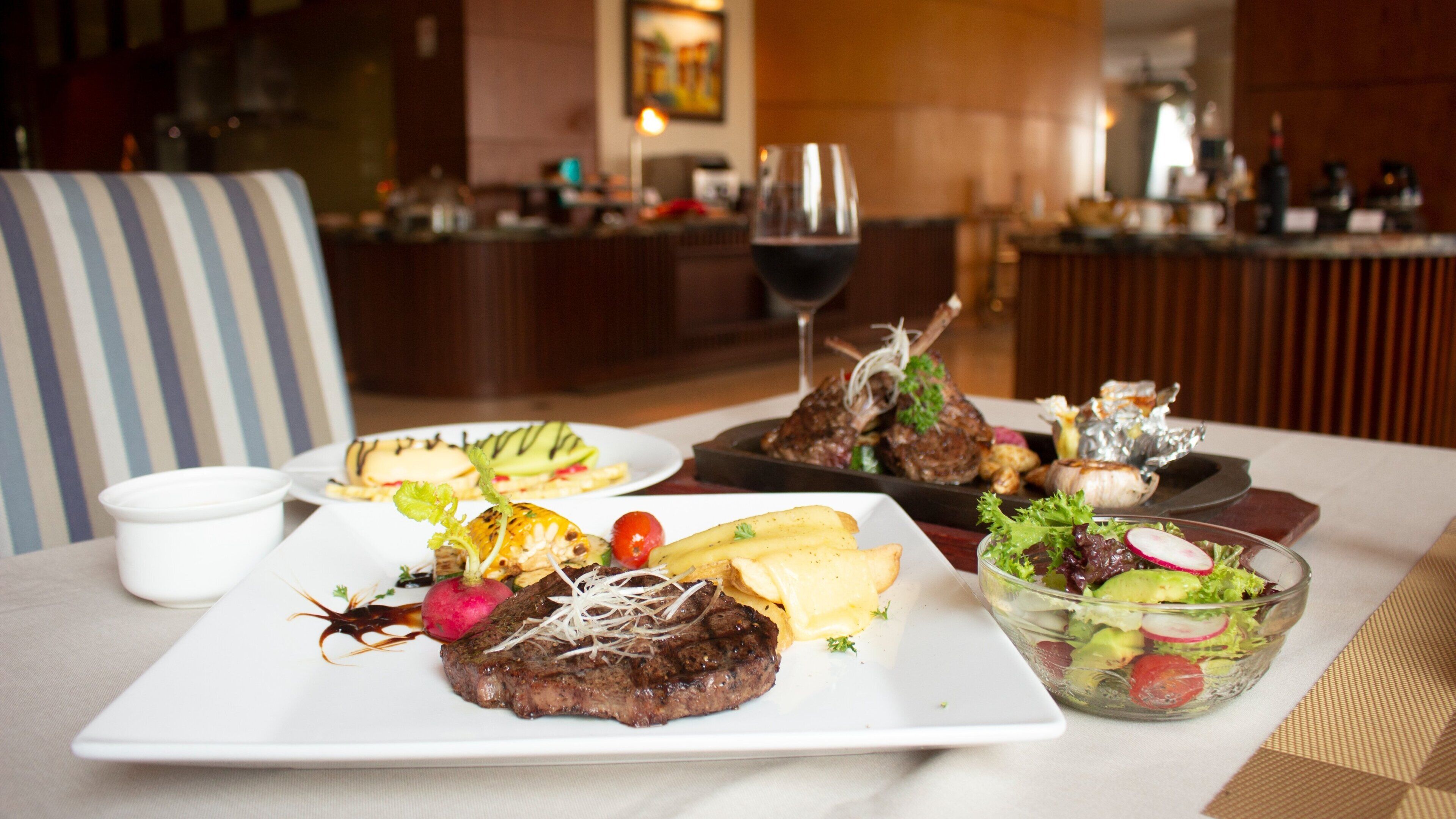 A dining table with various dishes, including steak, fries, and a salad.