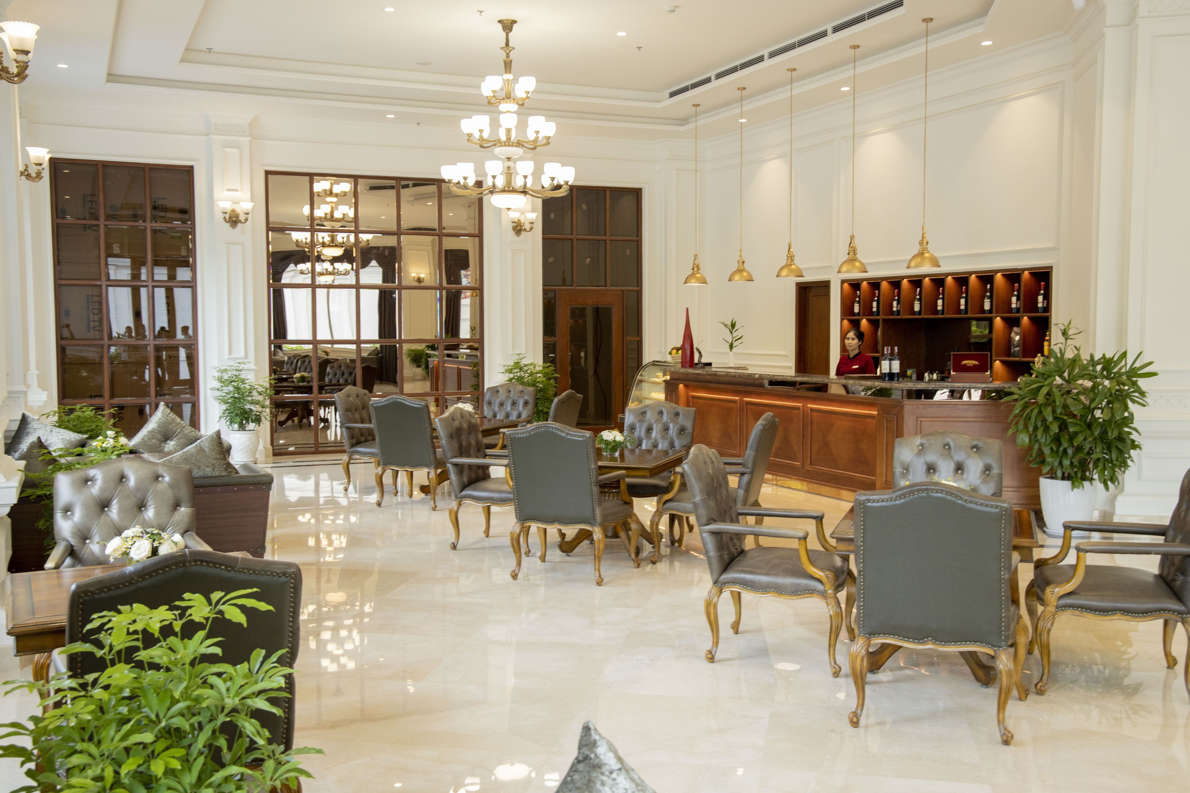 A spacious lobby with a polished floor, elegant seating, a bar area, and large windows.