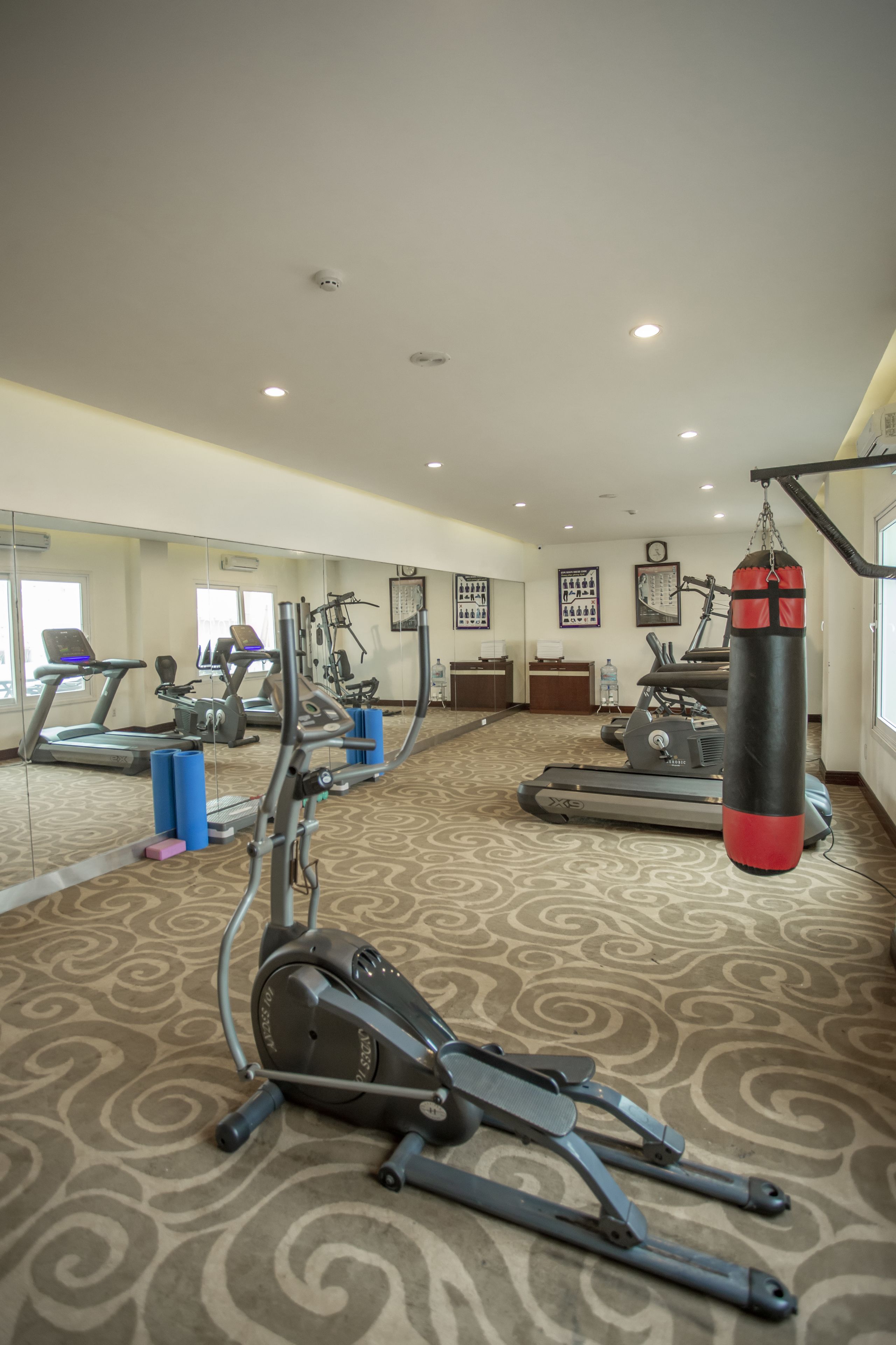 A gym with exercise equipment, a punching bag, and a large mirror.
