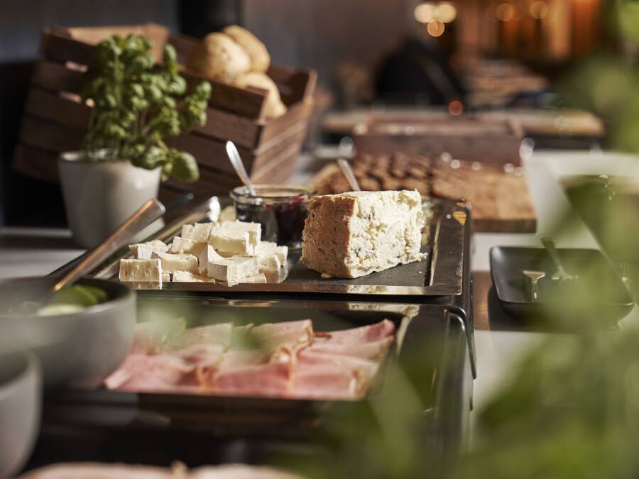 A buffet with various food items including cheese, bread, and meats.