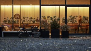 Un edificio moderno con amplios ventanales, una bicicleta estacionada afuera y plantas en macetas.