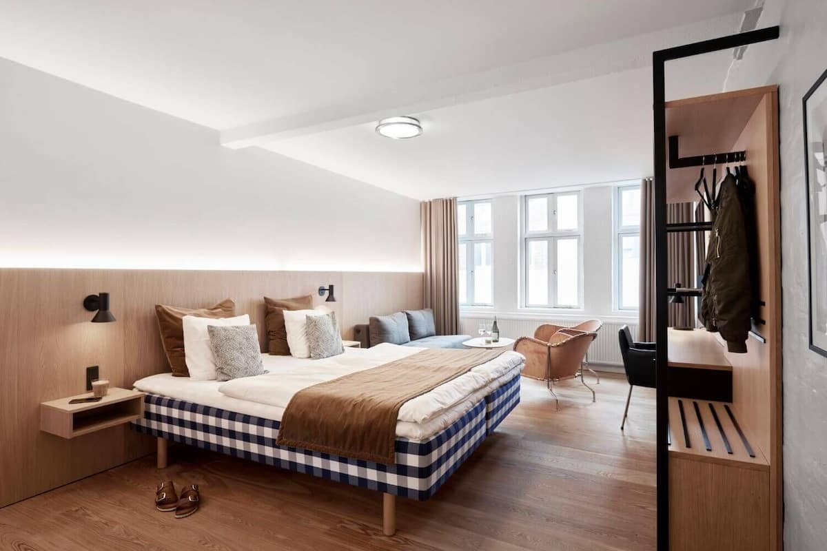 Une chambre moderne avec un grand lit, des tables de chevet, une chaise et une armoire intégrée.