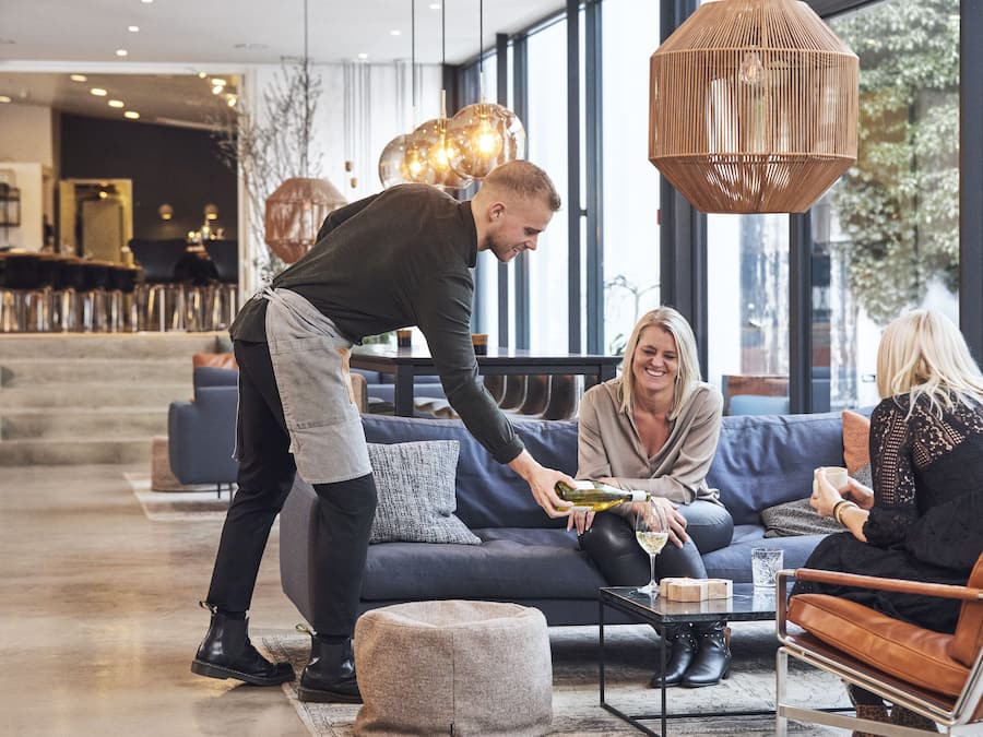 Eine moderne Hotelhalle mit Sitzgelegenheiten, großen Fenstern und zeitgemäßer Beleuchtung.
