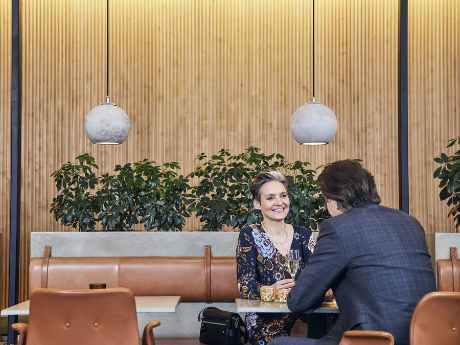 A restaurant with wooden panel walls, leather booths, and hanging spherical light fixtures.