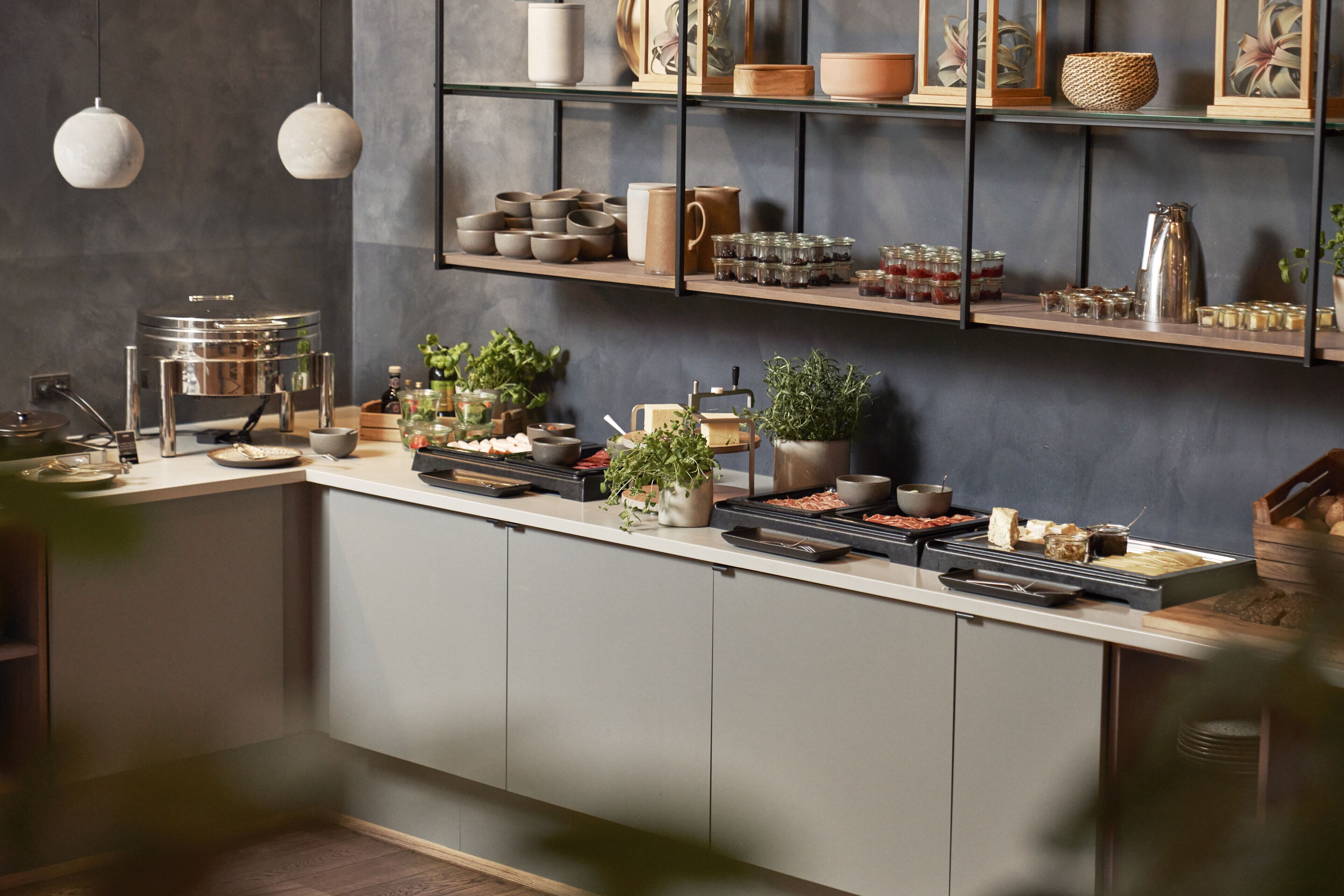 Una cucina moderna con un lungo piano di lavoro, diversi elettrodomestici e scaffali con utensili da cucina.