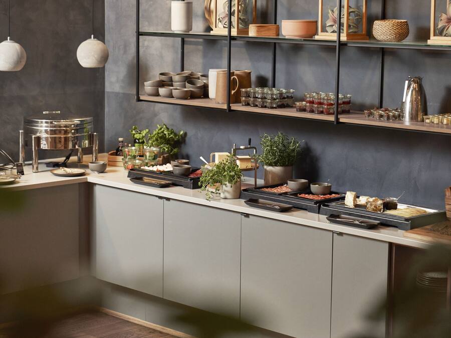 Una cocina moderna con una encimera amplia, diversos electrodomésticos y estantes con utensilios de cocina.