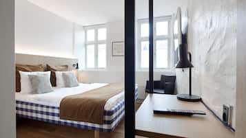 Una habitación de hotel con una colcha a cuadros, un escritorio con un control remoto y un ventanal con vistas.