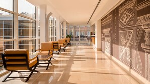 A spacious hallway with large windows, modern seating, and decorative wall art.