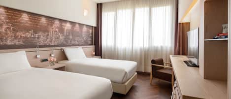 Habitación de hotel con dos camas, un escritorio, una silla, un televisor y un mural grande en la pared.