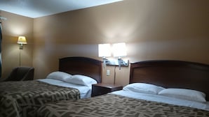 Camera d'albergo con due letti, un comodino, una lampada e una sedia.