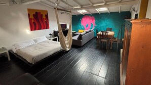 A room with a bed, a hanging chair, a sofa, a dining table, and a wall mural. - Bad - Bed & Breakfast and Design (Catania)