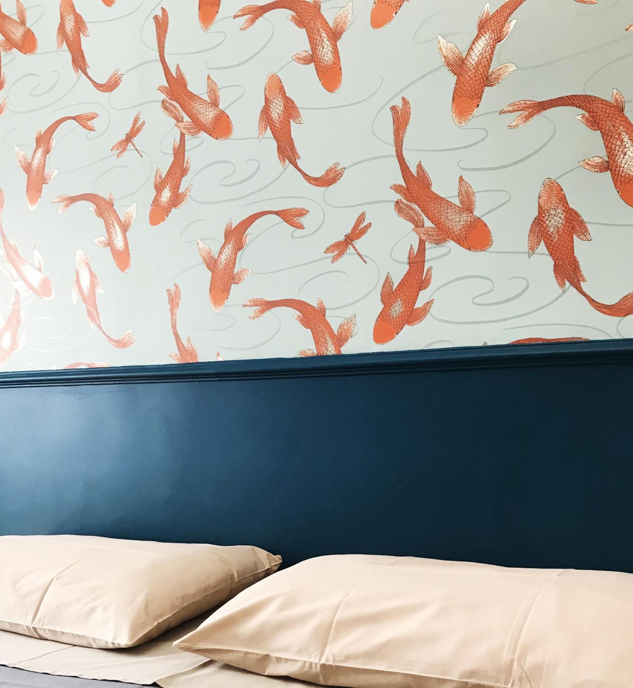 A room with a patterned wall and a dark blue headboard.