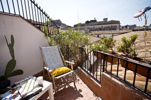 A balcony with a chair, a cactus, and a table with magazines. - Bad - Bed & Breakfast and Design (Catania)