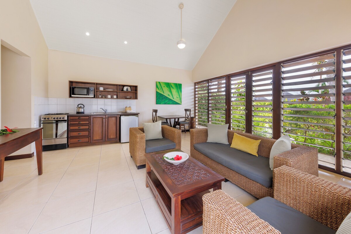 A modern kitchen with built-in appliances and a dining area with wicker furniture.