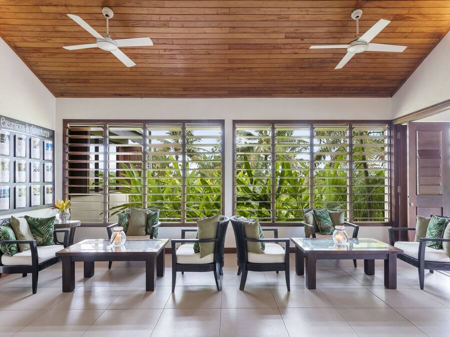 Amplio espacio interior con techo de madera y grandes ventanas que ofrecen vistas de exuberante vegetación.