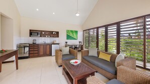 A modern kitchen with built-in appliances and a dining area with wicker furniture. - Mangoes Resort (Port Vila)