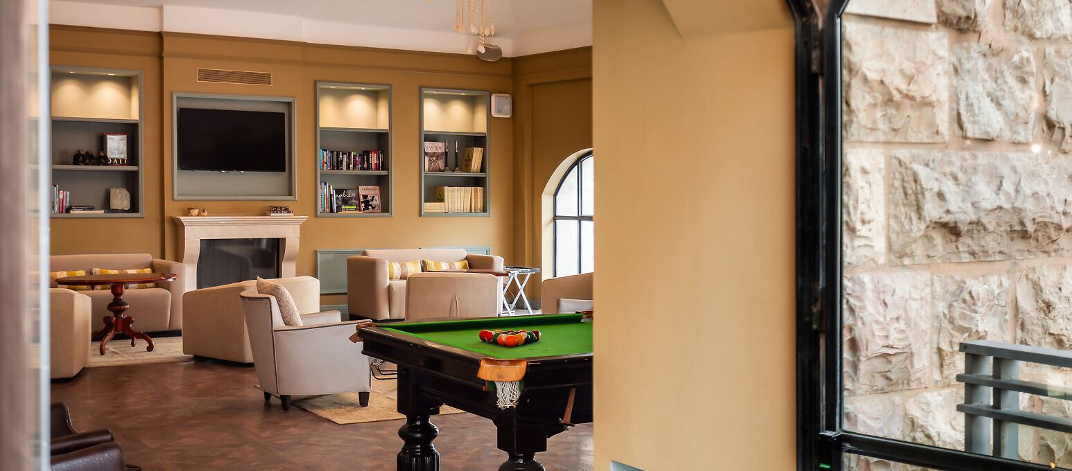 Una sala de estar con mesa de billar, sofás, chimenea y estanterías.