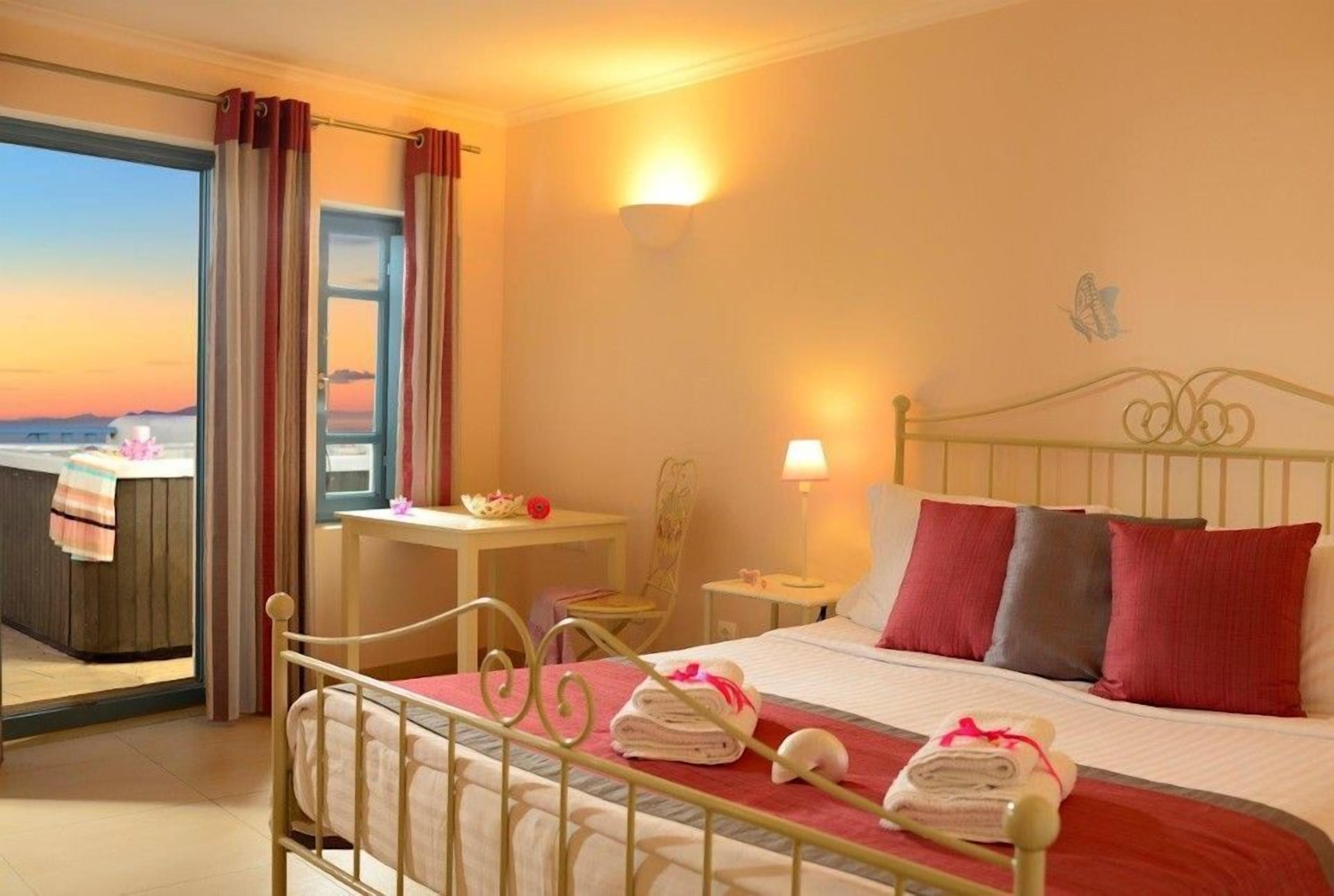 Una habitación de hotel con cama, mesitas de noche, escritorio y vistas al mar.