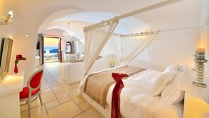 A spacious bedroom with a four-poster bed, a red chair, and a view of the sea through an open door. - Absolute Bliss (Santorini)