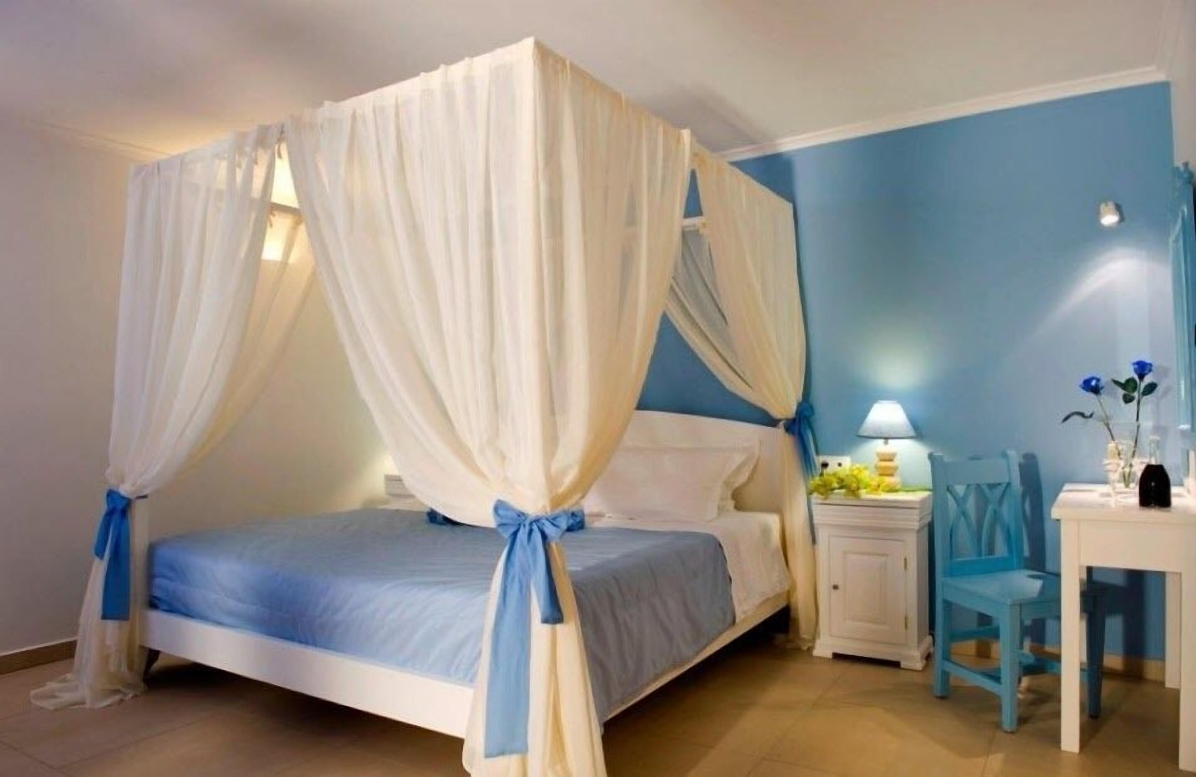 Un dormitorio con cama, mesita de noche, silla y mesa.