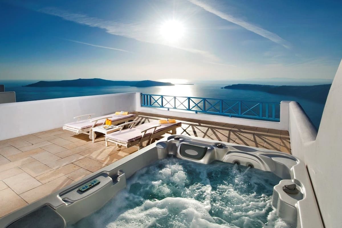 A hot tub on a balcony with a view of the sea and mountains.