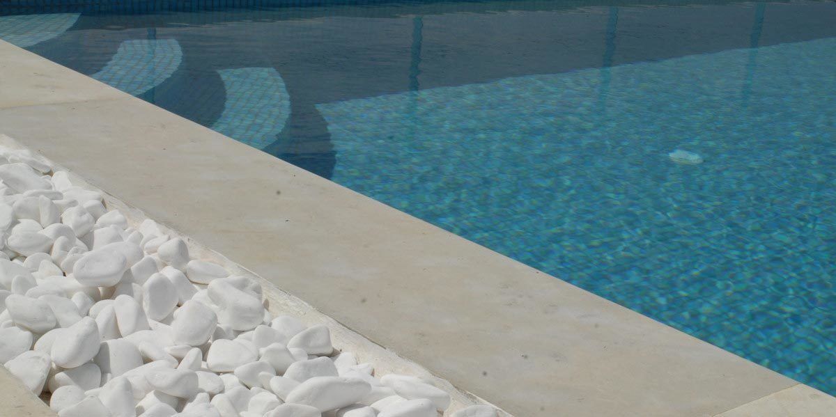 A clear pool with a pebble border and a tiled edge.