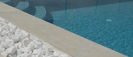 A clear pool with a pebble border and a tiled edge.