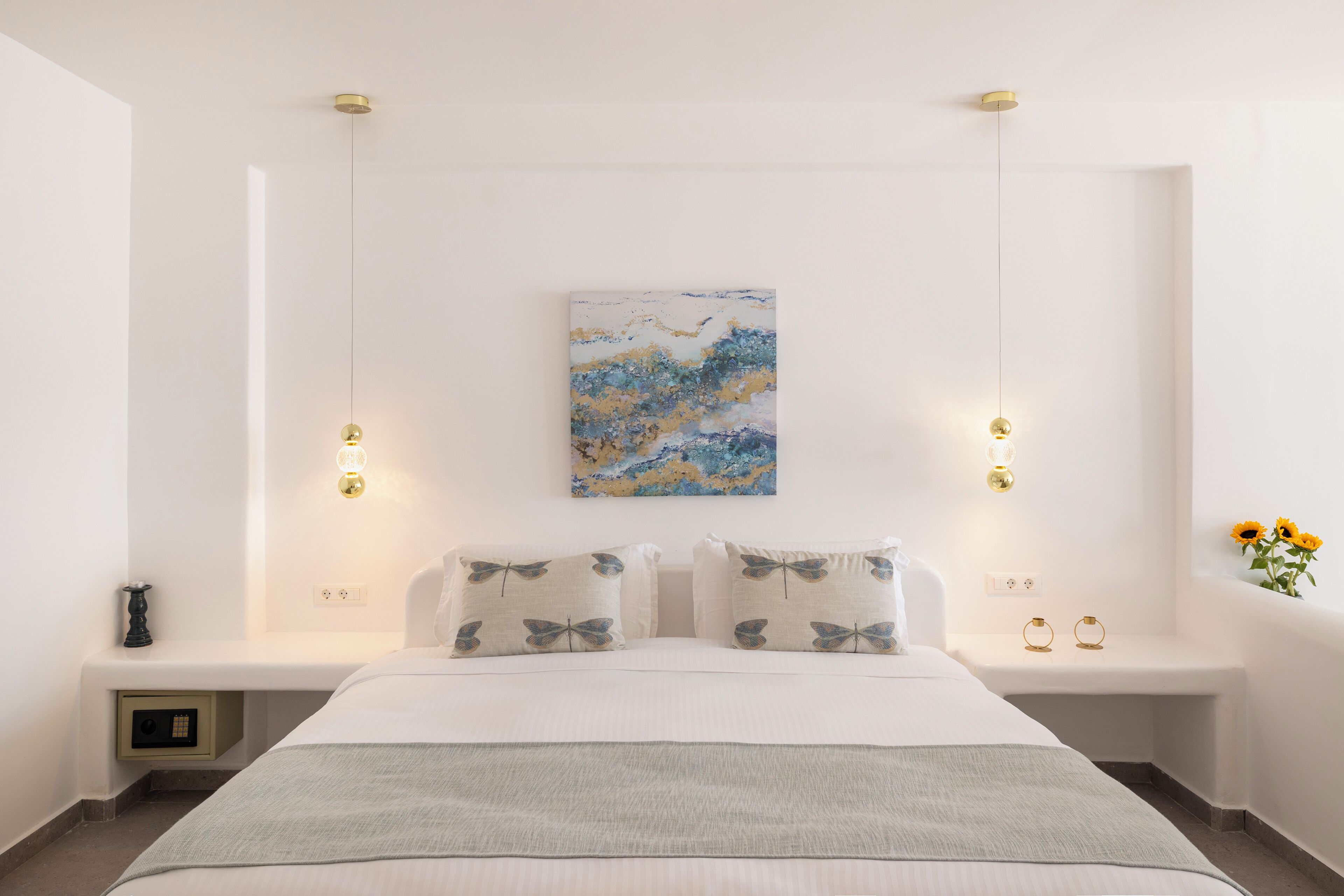 A modern bedroom with a large bed, bedside tables, a wall-mounted artwork, and pendant lights.