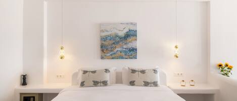 A modern bedroom with a large bed, bedside tables, a wall-mounted artwork, and pendant lights.