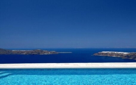 A clear view of a swimming pool with a horizon of rocky islands and the sea.