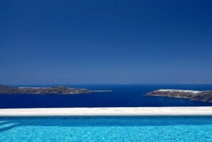 A clear view of a swimming pool with a horizon of rocky islands and the sea. - Absolute Bliss (Santorini)