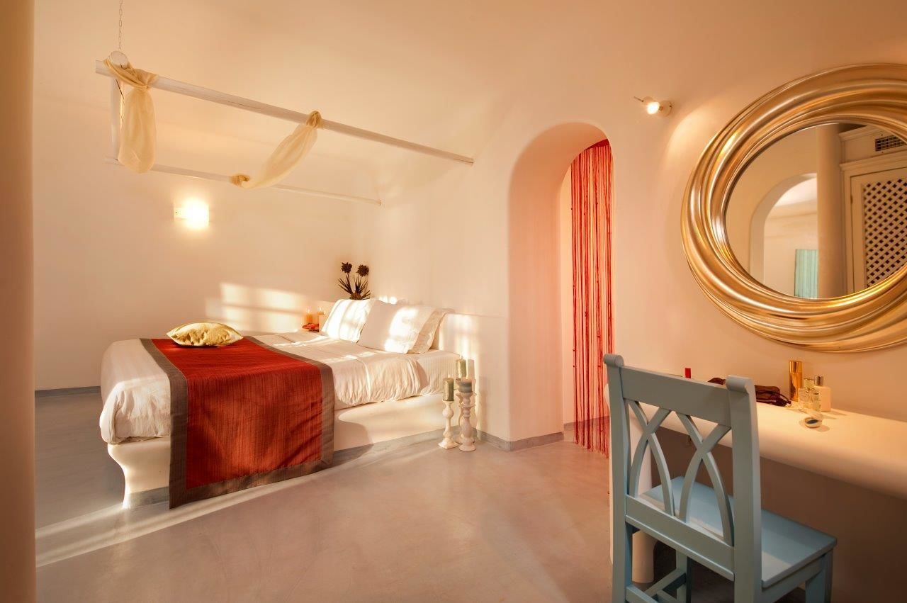 Un dormitorio con cama, mesita de noche, espejo y una silla.